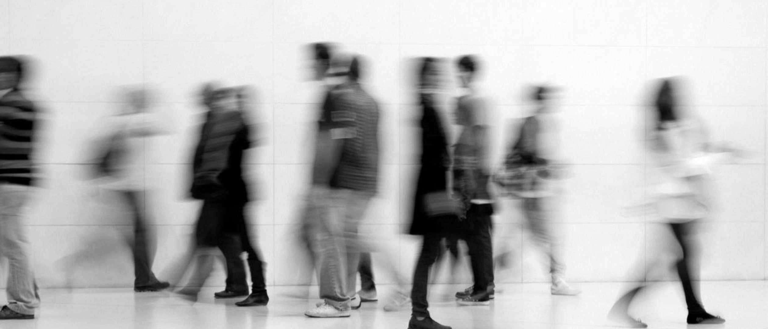 People walking in motion through a bright open space, monochrome